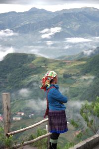 Rear view of woman standing on railing against mountain