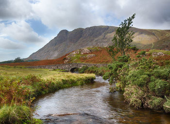 Scenic view of river by mountains against sky