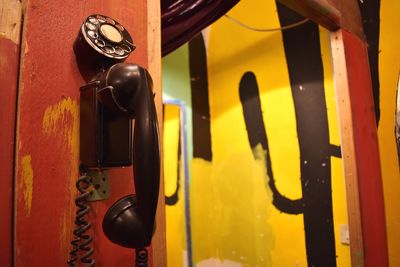 Close-up of rotary phone attached to wall