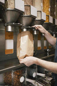 Cropped image of owner filling food in paper bag while working in store