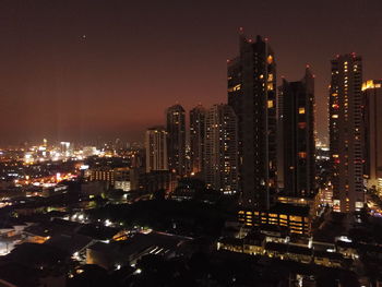 Illuminated buildings in city against sky at night