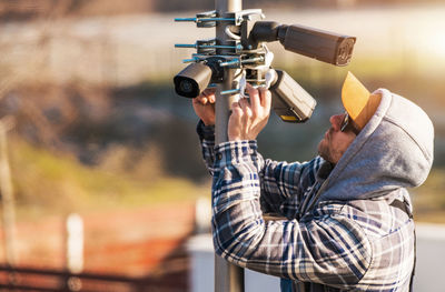 Man repairing cctv cameras on pole