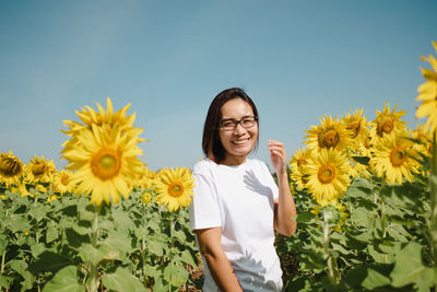 Portrait of young woman standing amidst sunflowers