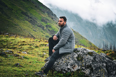 Side view of man sitting on a rock