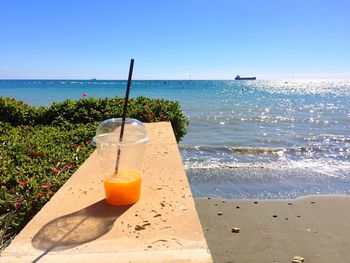 Drink on table by sea against sky