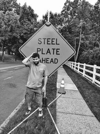 Man standing against road sign
