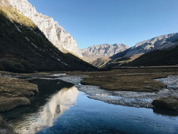 Scenic view of lake and mountains against clear blue sky
