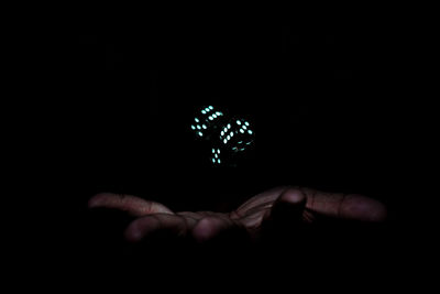 Close-up of hand holding glass over black background