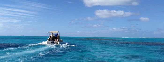 Men riding boat in sea against sky