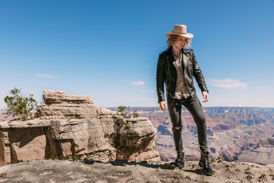 Man standing on rock against sky