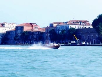 Boats moored in sea with buildings in background