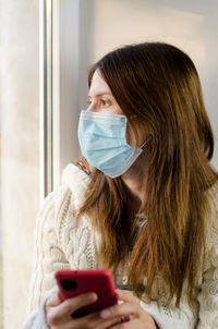 Woman in a medical mask with a phone in her hands. self-isolation during a pandemic