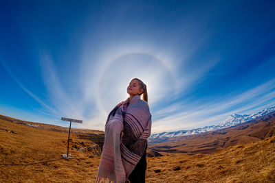Full length of woman standing on land against sky and halo