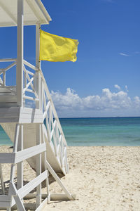 Lifeguard tower with yellow flag on a tropical beach. 