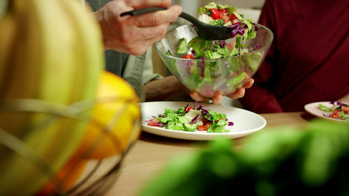 Midsection of men eating salad