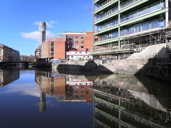 Urban buildings and their reflection  in bristol's floating harbour, set against sky