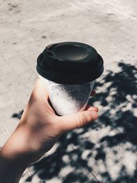 Cropped hand holding disposable cup at street