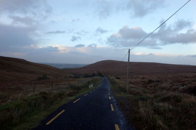 Road leading towards mountain against sky