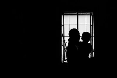 Silhouette mother with child near window