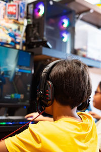 Wearing headphone, a gamer  in a room playing with friends on the networks in video games.