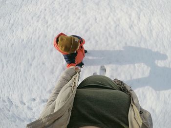 Low section of woman walking with son on snowy field