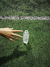 Cropped hand reaching for water bottle on playing field