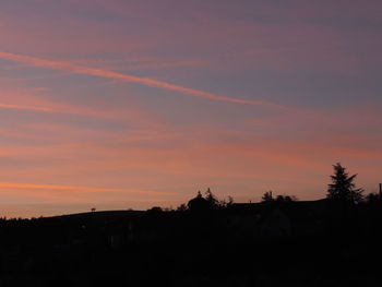 Silhouette trees and buildings against sky during sunset