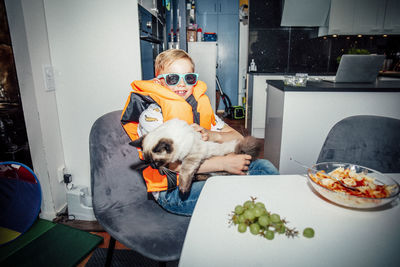 Portrait of smiling boy with cat at table