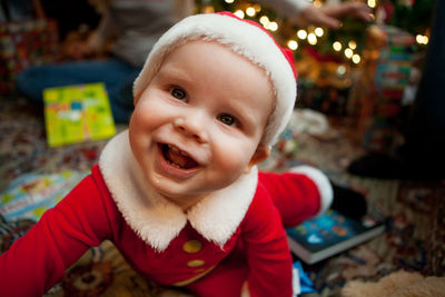 Close-up of cheerful baby boy wearing santa hat at home