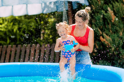 Mom and daughter have fun in the pool in the garden, dipping into the warm water