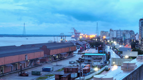 High angle view of illuminated city by sea against sky