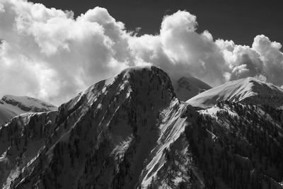 Scenic view of snowcapped mountains against cloudy sky