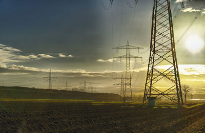 Electricity pylon on field against sky during sunset