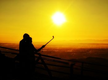 Man fishing on calm sea at sunset