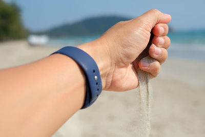 Midsection of man hand on sea shore