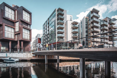 Canal by buildings against sky in city