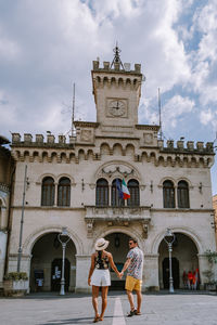 People on building against cloudy sky