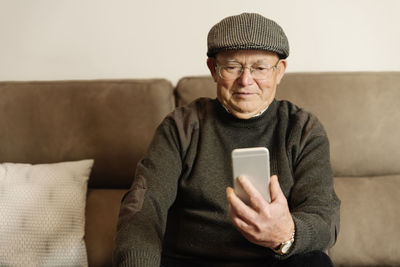 Senior man using smart phone sitting at home