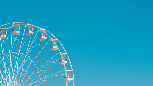 Part of ferris wheel in front of blue sky