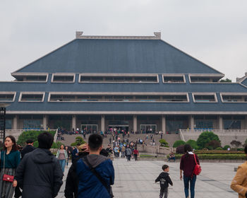 People walking on building against sky in city