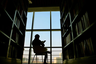 Silhouette man sitting by window in building