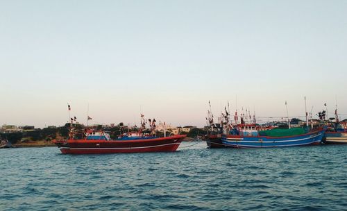 Boats in sea against clear sky