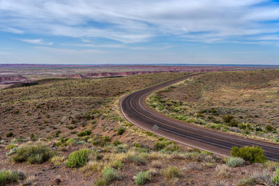 Road passing through land against sky