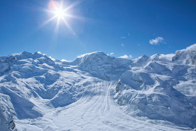 Low angle view of snow mountains against blue sky