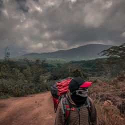 Rear view of person with umbrella on mountain against sky