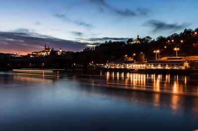 Illuminated bridge over river against sky at night