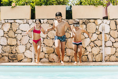 Siblings jumping in swimming pool