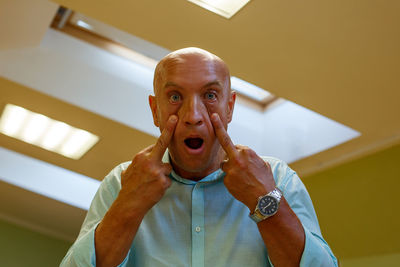Bald annoyed middle-aged man wearing casual shirt, amazed and surprised