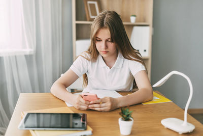 A beautiful girl is sitting at a table and preparing for exams