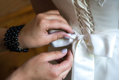 Cropped hands of woman assisting bride in dressing up